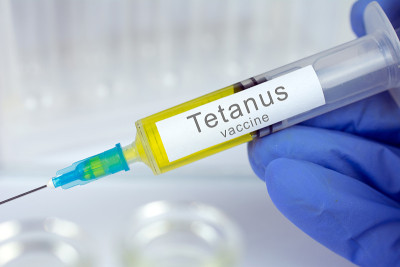 医生或护士的手在医疗手套与医疗注射器准备注射一针破伤风疫苗。特写，选择性聚焦