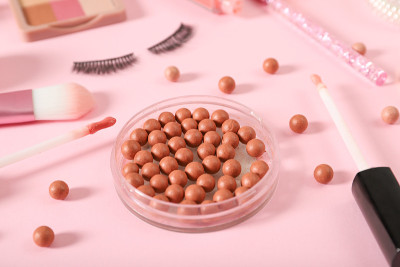 粉色背景上的球状腮红和装饰性化妆品。