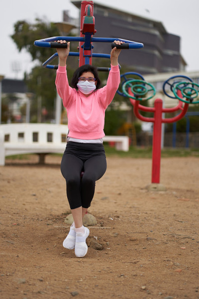 新常态女人在公园里用机器做俯卧撑。戴口罩或口罩的妇女和运动服。体育会议
