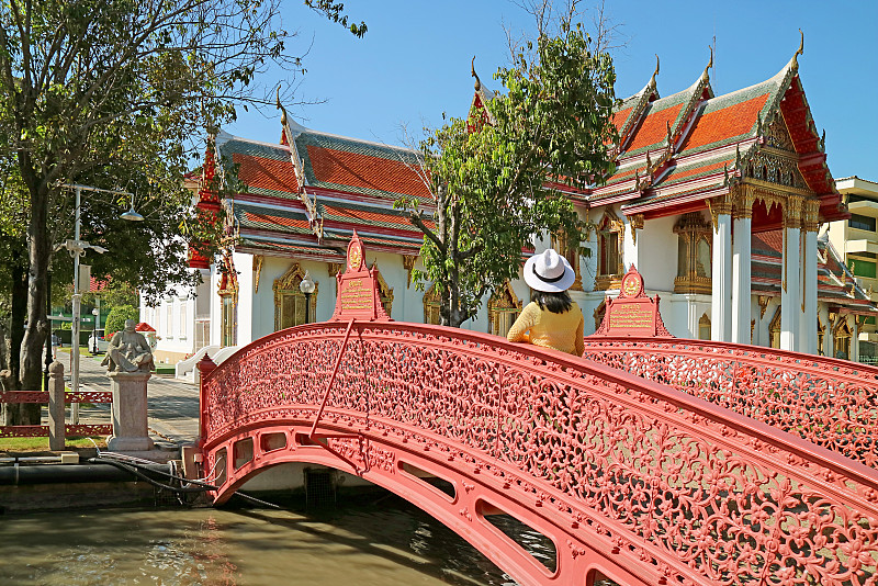 泰国曼谷，历史寺庙，穿过大理石寺庙内运河的美丽弯曲桥上的女性游客