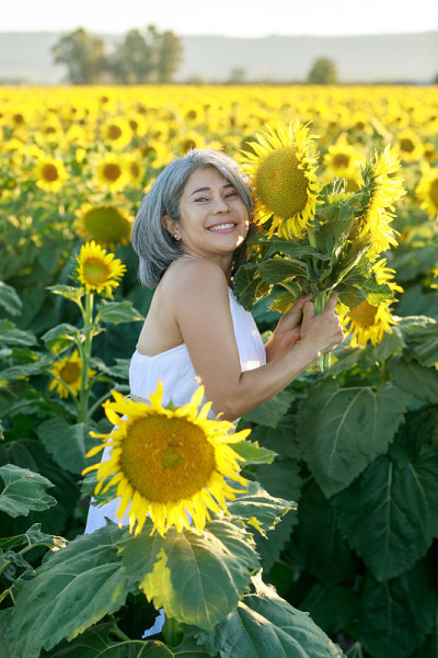 白衣女子站在夏日盛开的向日葵田里