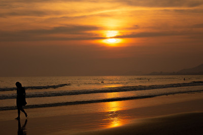 柔和的海浪和泡沫在海滩上与日落的天空背景。