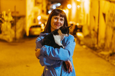 猫。在夜色中的城市背景下，女孩抚摸着一只猫。意大利。