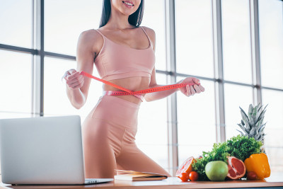拿着卷尺。身材苗条、皮肤干净的女性在室内穿着运动服