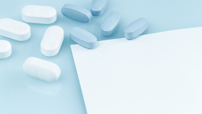 几片白色和蓝色的药片或药丸在桌子上。医学和药学
