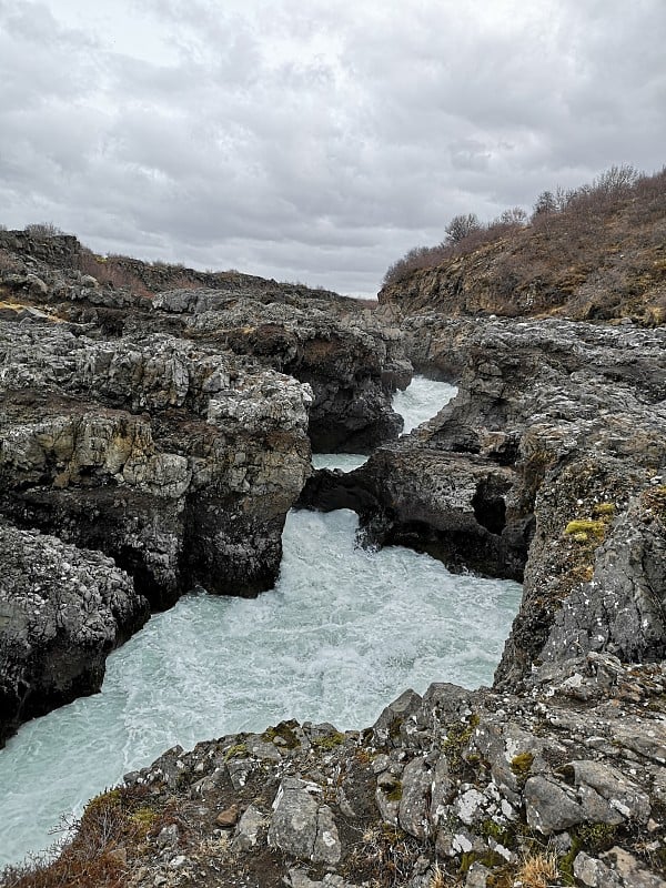 冰岛巨大的Hraunfossar瀑布在巨石之间流动。