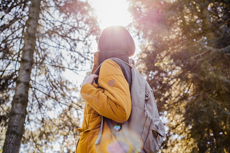 背着背包在树林里徒步旅行的年轻女子