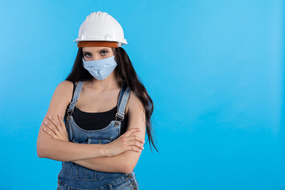 一名戴着头盔和防护面具的年轻女子在建筑工地等待上级的命令。
