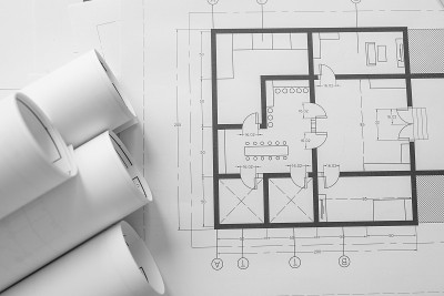 建筑师将房屋平面图卷起来放在桌面上，高角度查看。