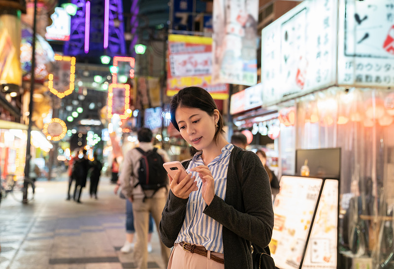 一个亚洲女人在街上打电话。