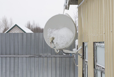 一场雪后，卫星天线被固定在一所房子的墙上