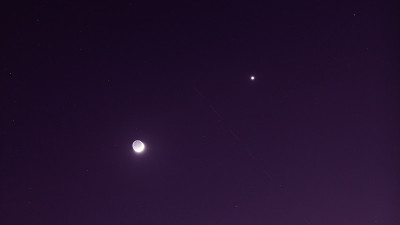 月亮和金星在黑暗的夜空中，卫星的轨迹可以在黑暗的夜空中看到。