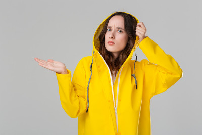 漂亮的黑发女孩穿着黄色雨衣检查是否下雨了。准备好迎接坏天气吧。