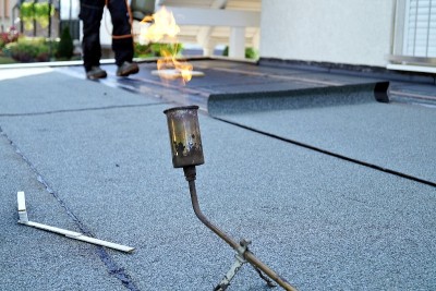 在屋顶毛毡施工期间，用丙烷喷灯安装平屋顶。加热和熔化沥青屋顶毡。