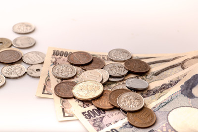 白色的桌子上放着日本的硬币、钞票和护照