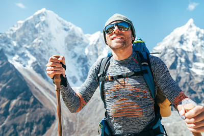 在塔波切6495米和Cholatse 6440米的山峰上微笑的徒步者的肖像，背景是徒步杆，紫外线防护