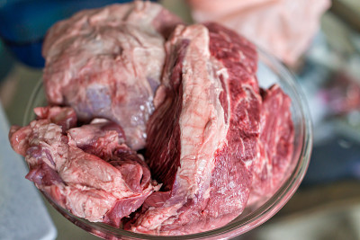 玻璃大碗与大块的全牛肉烤生红肉与模糊的背景和纹理烹饪配料