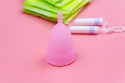 粉色背景的卫生巾，卫生棉条和月经杯。关键日子、月经、女性卫生的概念