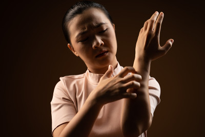 亚洲妇女是刺激物瘙痒她的皮肤孤立站在米色背景。