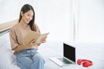 放松女人拿着书在大学图书馆的书架上阅读。少妇放松阅读，翻开书本，休闲心灵。聪明漂亮的女人聪明的人在知