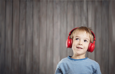 Little boy on wooden background with red headphone