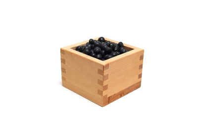 黑色的大豆在白色的背景上孤立在木箱里。