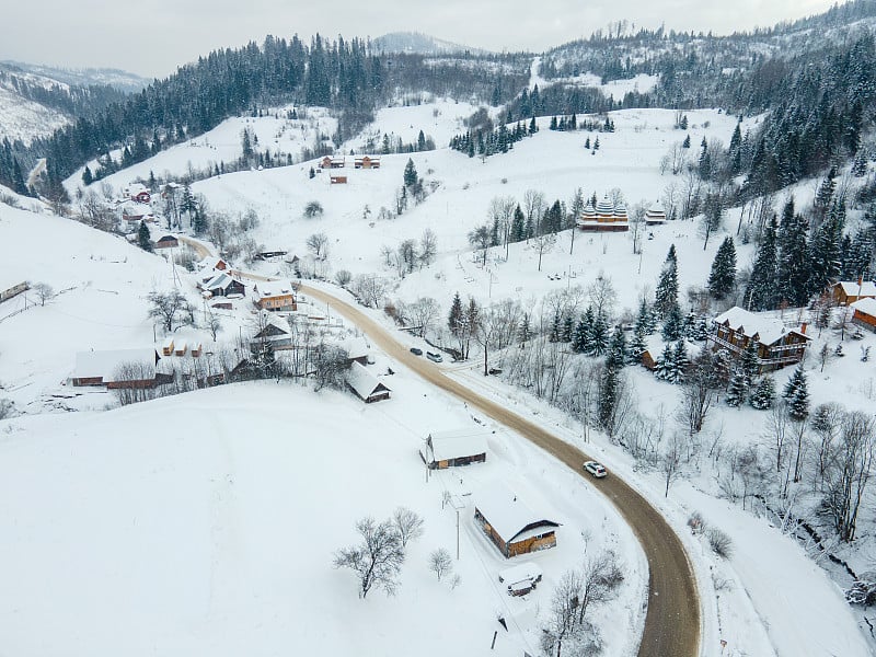 喀尔巴阡山脉中被雪覆盖的村庄的公路鸟瞰图