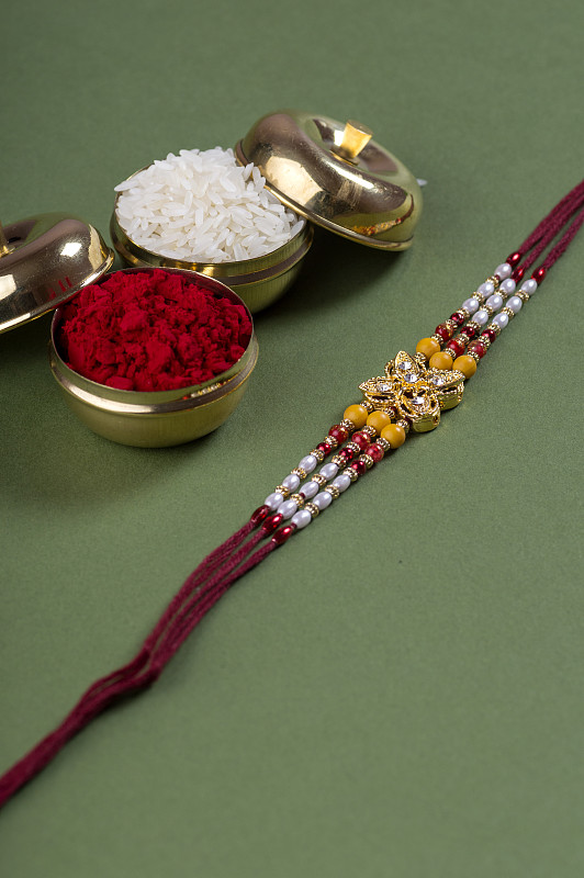 印度节日:Raksha Bandhan背景与优雅的Rakhi，米粒和Kumkum。一种传统的印度腕带