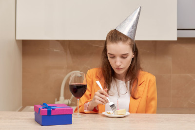 年轻女子在吃生日蛋糕。戴着一顶银色的喜庆帽子。
