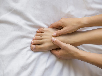 年轻女子在床上按摩她的脚。、医疗保健的概念