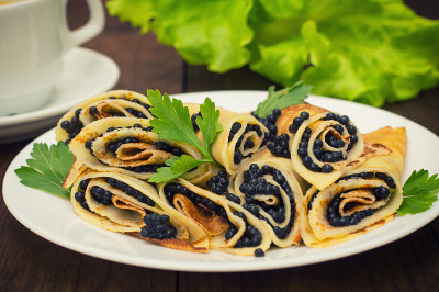 黑鱼子酱煎饼卷。俄罗斯菜。平的。Maslenitsa。木制背景。特写镜头