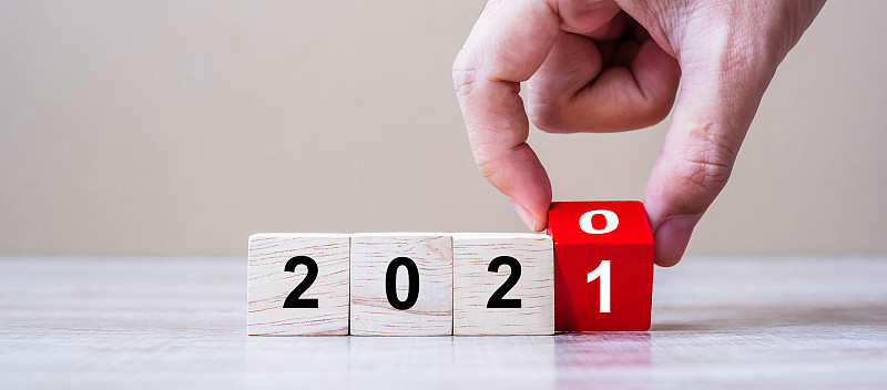 商人手翻转木质立方体块与2020年改变到2021数字文本在桌子的背景。新年决心，战略，计划，开始，目
