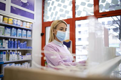 顾客戴着防护口罩在药店购物。