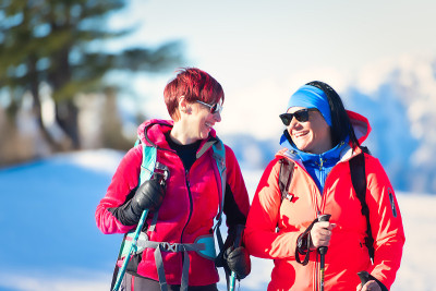 快乐的年轻女子夫妇在雪地徒步旅行