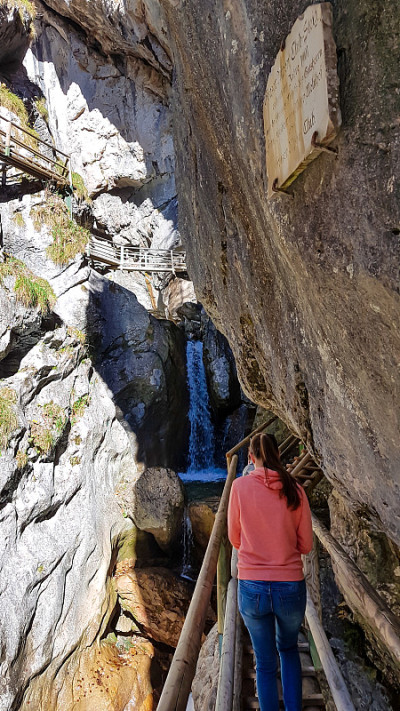 Baerenschuetzklamm——一名身穿粉色连帽衫的女子在奥地利阿尔卑斯高山峡谷的木制梯子上