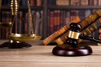 律师事务所的老式办公室，桌子上放着一把法律锤子和一个旧地球仪，背景是一些法律书籍