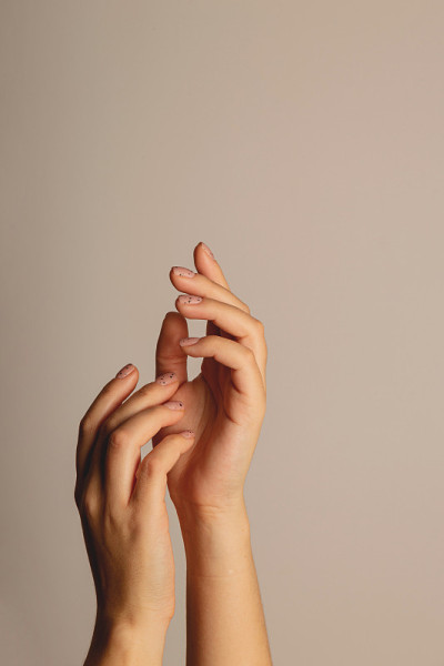 女人的手往上伸。以极简主义美甲在黑暗的背景