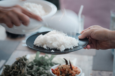 运动模糊的手，正在舀茉莉花米煮成一道菜。泰国香米。