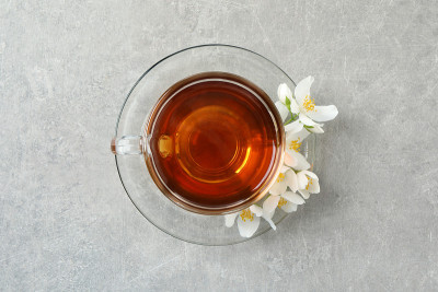 灰色的桌子上放着一杯香喷喷的茉莉花茶和鲜花，俯视图