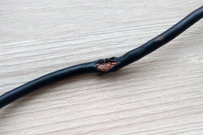 木桌或地板背景被老鼠黑色电线损坏。危险的破损电力电缆