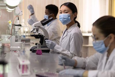 年轻女化学家戴着防护面具看着你在工作场所