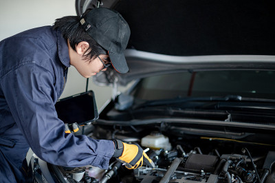 亚洲汽车技师用平板电脑检查汽车