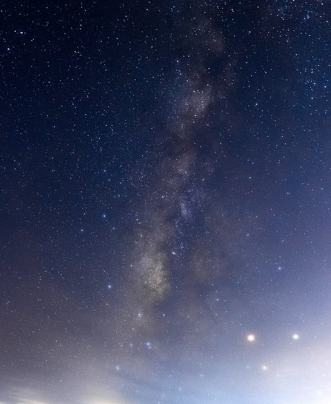 蓝色的夜空，银河和黑暗的背景上的星星。噪音和谷物。照片长曝光和选择白平衡。