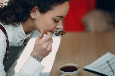 杯子品尝女孩品尝品尝咖啡质量测试。咖啡拔火罐