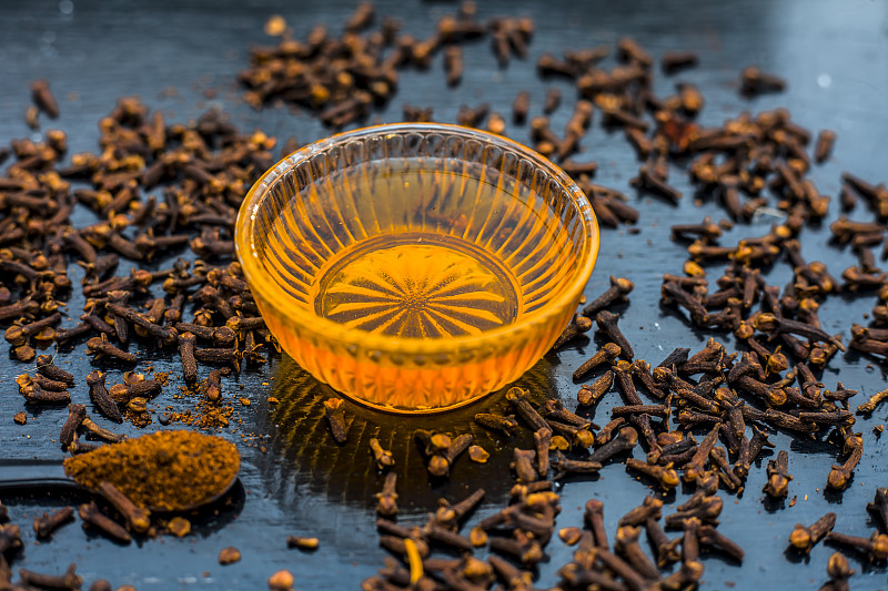 草药和阿育吠陀治疗或治疗哮喘:干燥的丁香与蜂蜜在木制表面。