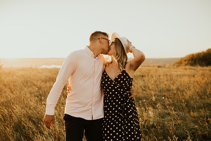 guy with a girl in hat walking in meadow