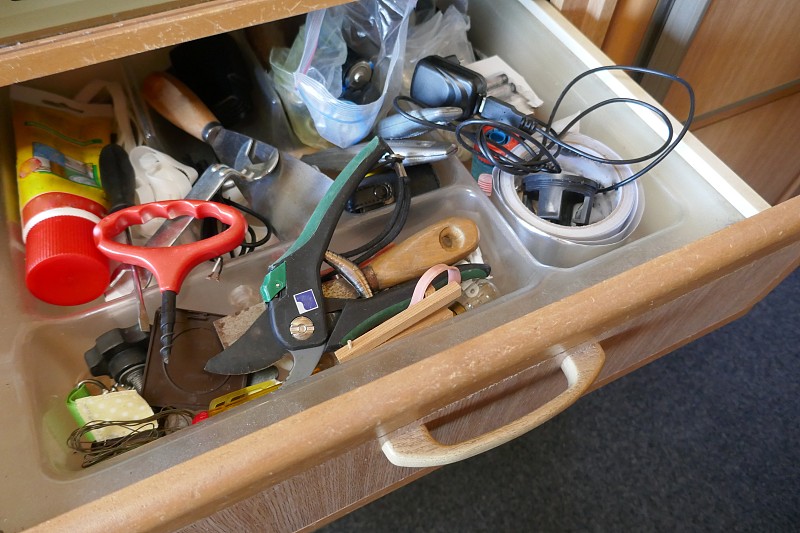 在看一个不整洁的抽屉。杂乱的抽屉里有工具、家居用品和各种其他物品