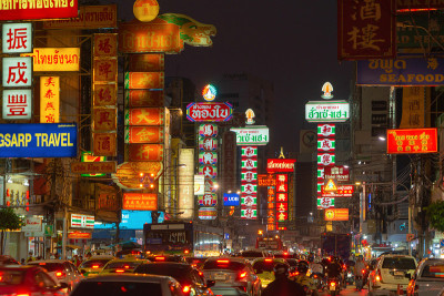 泰国曼谷Yaowarat路夜市街。这个著名的旅游景点到处都是中文广告招牌。汽车的游客与广告牌。中国城