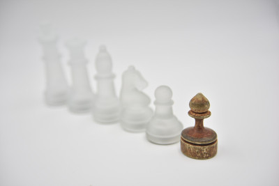 玻璃象棋人物后面的木制庞塞在白色的背景
