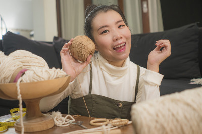 亚洲女孩享受流苏手工爱好-年轻快乐和漂亮的日本人在家里做macramé使用绳子，绳索和线在国内手工装